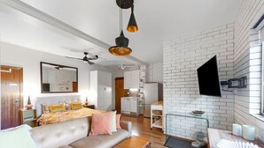 A modern living room with a sofa, coffee table, and a TV mounted on the wall. - Fi's Beach Pad (Port Macquarie)