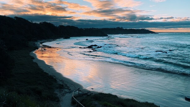 A coastal landscape with a curved shoreline, rocky outcrops, and a clear sky with clouds. - Fi's Beach Pad (Port Macquarie)