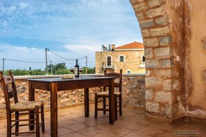 Ein Gebäude aus Stein mit einer gefliesten Terrasse und einem Tisch mit Stühlen.