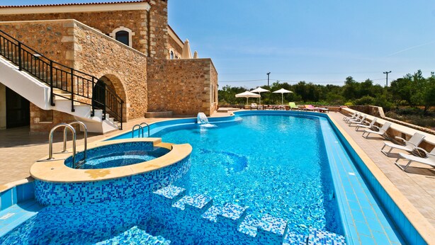 A swimming pool with a stone building, steps, and lounge chairs. - Independed Stone villa common pool (Παλαιλώνι)