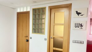 Quarto com duas portas de madeira, uma delas com painel de vidro, e uma parede com duas molduras.
