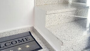 Uma escadaria com um tapete de boas-vindas na base.