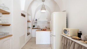 A narrow kitchen with white cabinetry, a central island, and a retro radio. - La Torre di Monsignore 12 2 (Fasano)