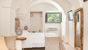 A bedroom with a bed, bedside tables, a window with a view, an air conditioner, and a mirror. - La Torre di Monsignore 12 2 (Fasano)