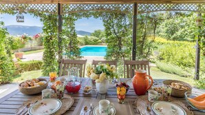A table set for breakfast with a view of a swimming pool and mountains in the background. - Casal Parro 6 in Perugia (Perugia)
