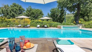 A swimming pool with lounge chairs and umbrellas, surrounded by greenery. - Casal Parro 6 in Perugia (Perugia)