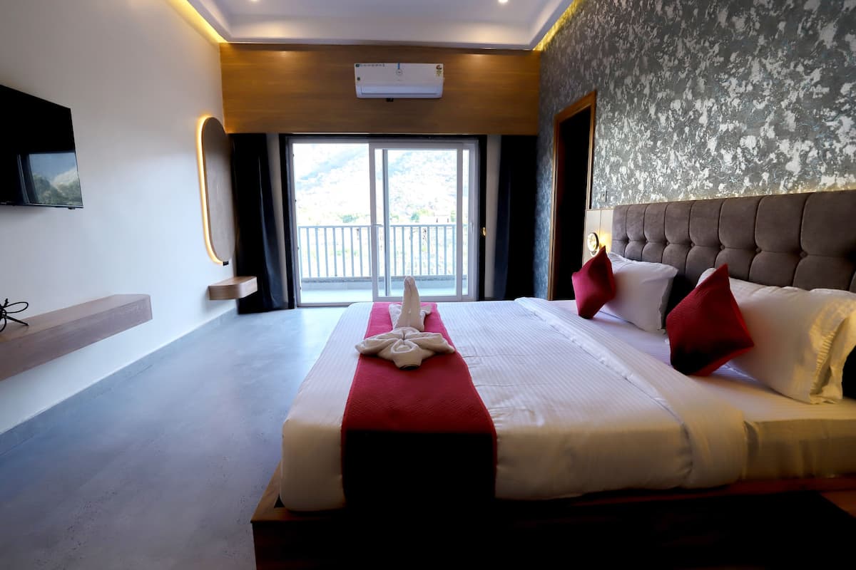 Una habitación de hotel con una cama grande, un televisor montado en la pared y un balcón con vistas.