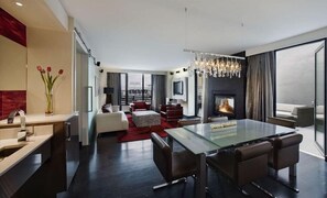 Una habitación de hotel moderna con una mesa de comedor de vidrio, una chimenea, un sofá y un televisor.