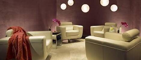 Une pièce moderne avec deux canapés, une petite table et un mur décoratif agrémenté de luminaires circulaires.