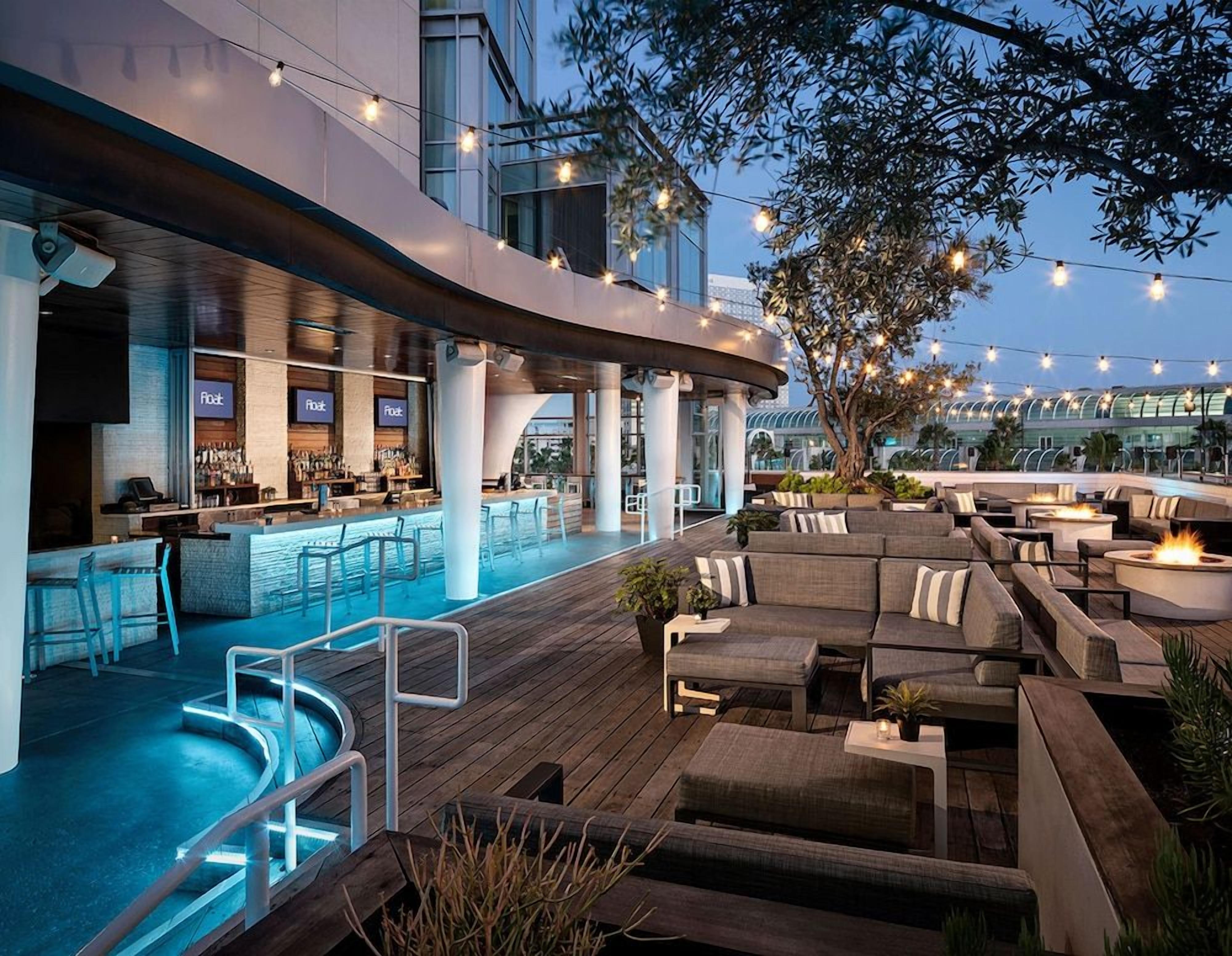 A rooftop bar with a pool, outdoor seating, and string lights.