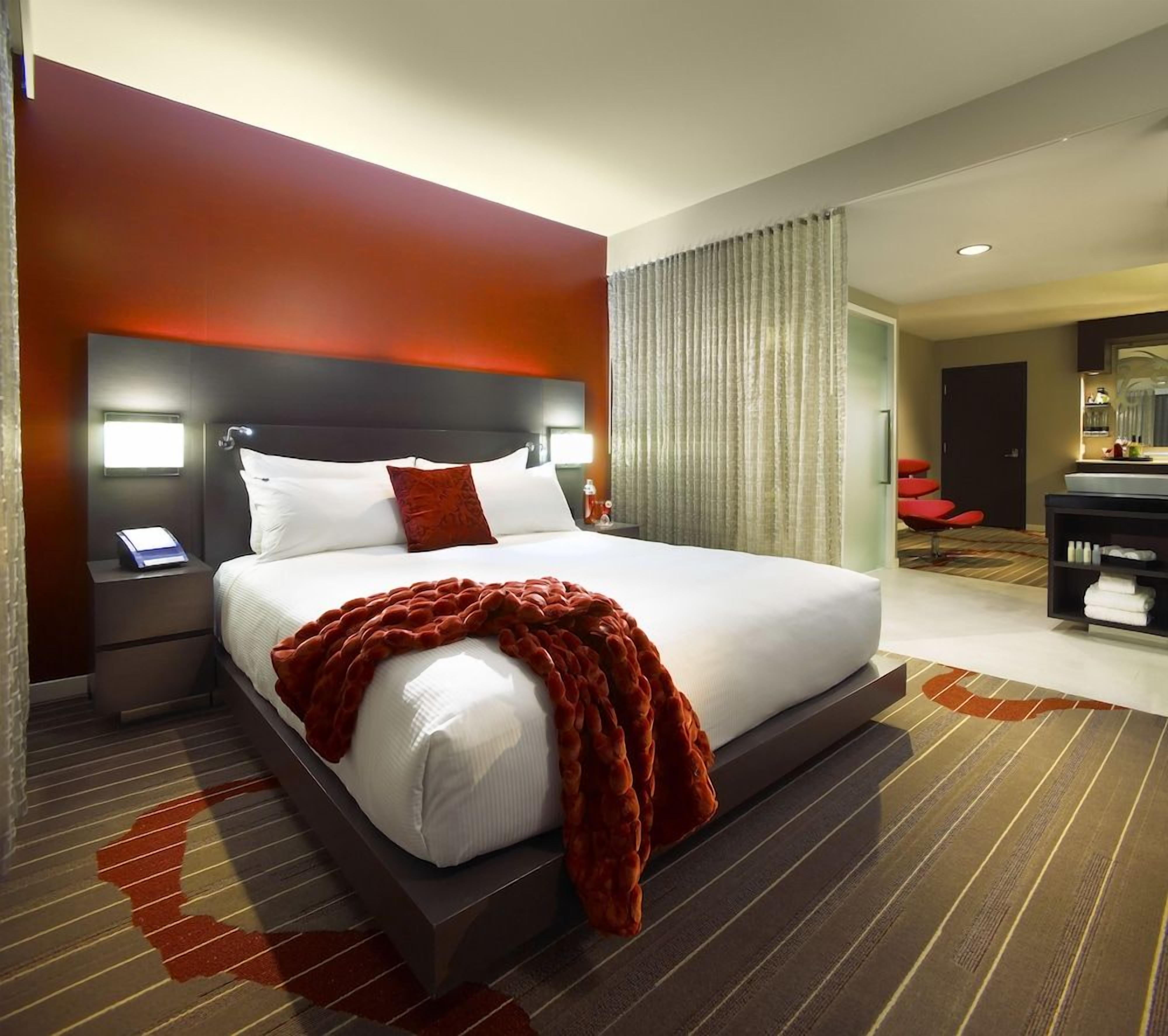 Ein Hotelzimmer mit einem großen Bett, einem Nachttisch mit Telefon, einem Schreibtisch mit Stuhl und einem Spiegel.