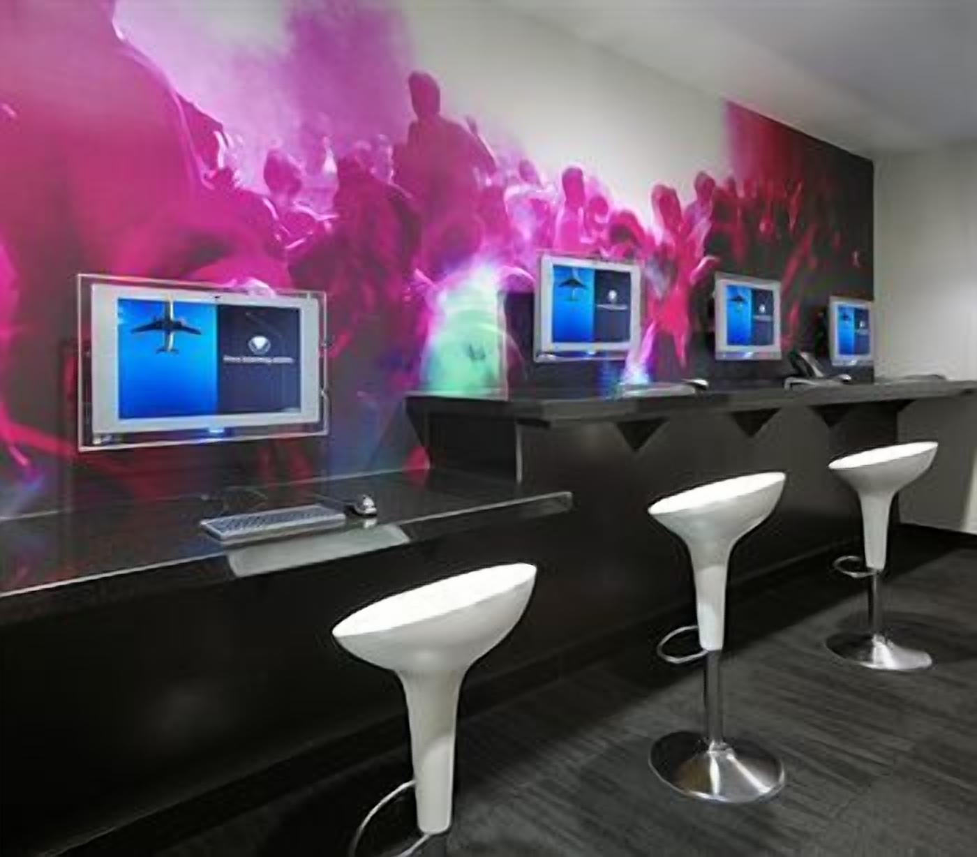 A bar area with multiple screens, bar stools, and a dark-colored counter.