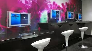 A bar area with multiple screens, bar stools, and a dark-colored counter.