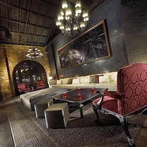 Un espace détente comprenant un canapé, des fauteuils, une table basse et un lustre.