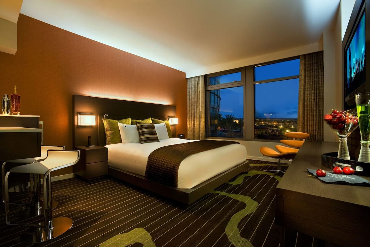 Habitación de hotel con cama, escritorio, silla y vista a la ciudad.