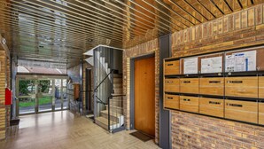 A modern interior with a wooden floor, brick walls, a staircase, and a glass door leading outside. - Chic apart with parking (Mantes-la-Jolie)