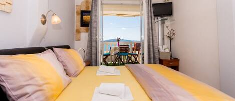 A hotel room with a bed, a TV, and a balcony with a table and chairs.