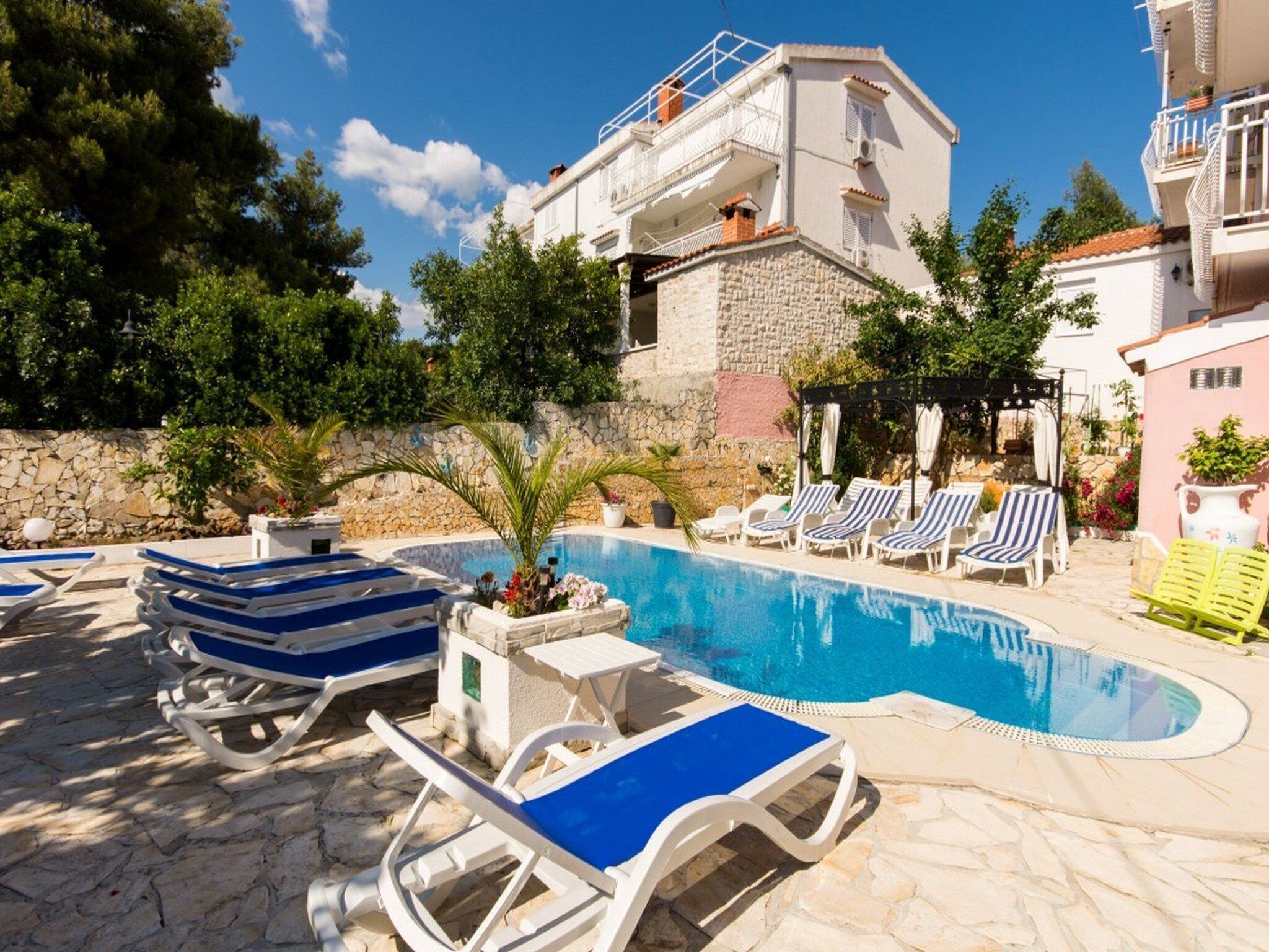 A swimming pool with lounge chairs and a stone wall.