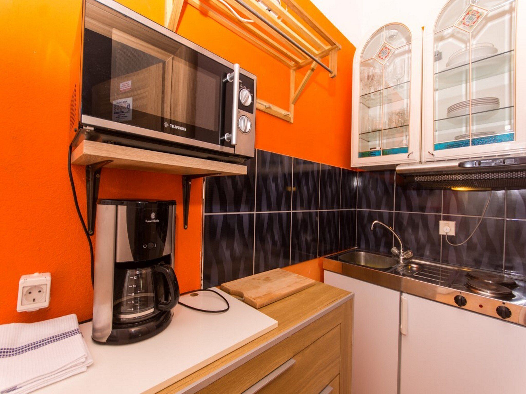 A compact kitchen with a microwave, coffee maker, and a sink.