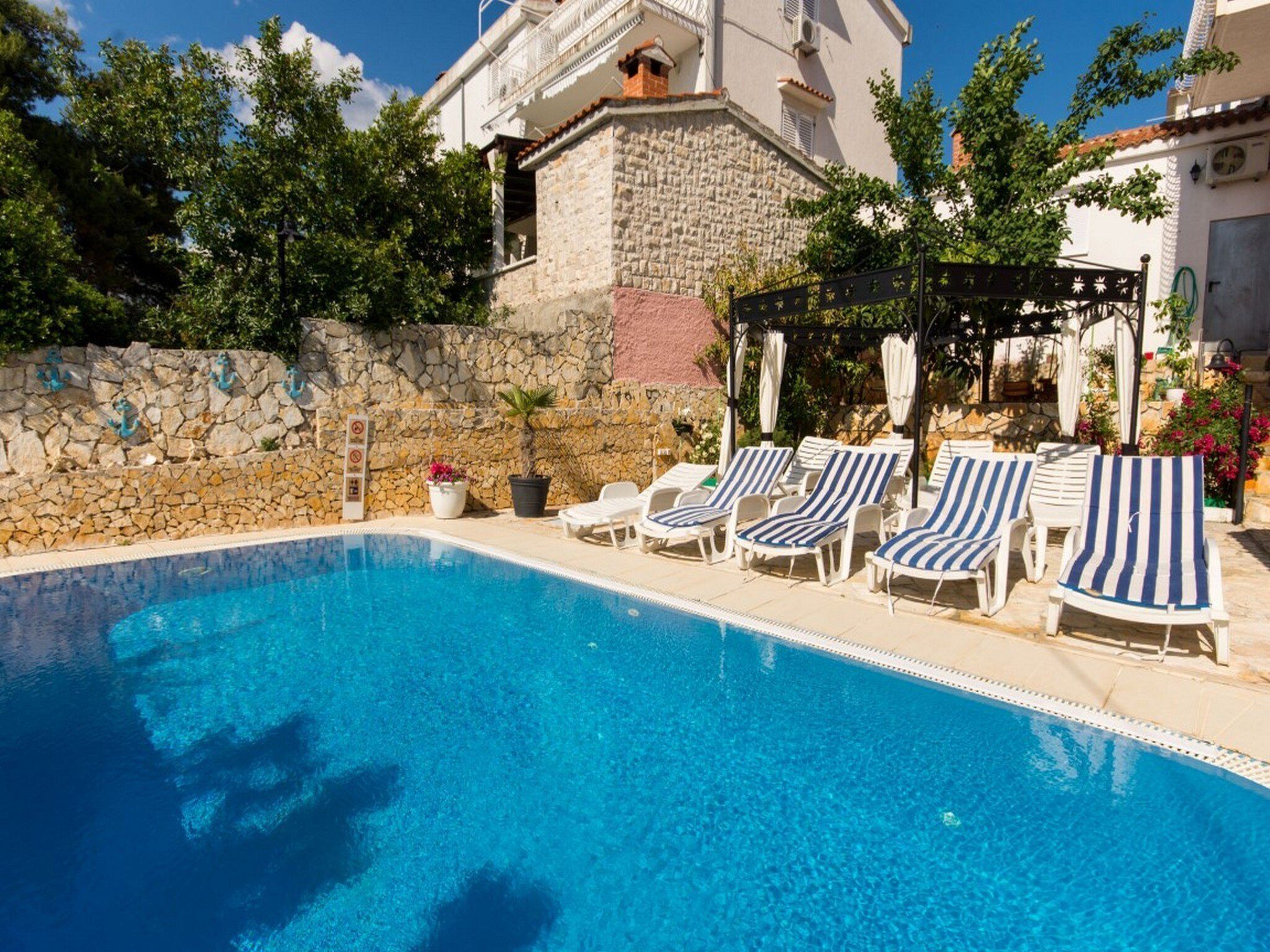 A swimming pool with lounge chairs and a stone wall.