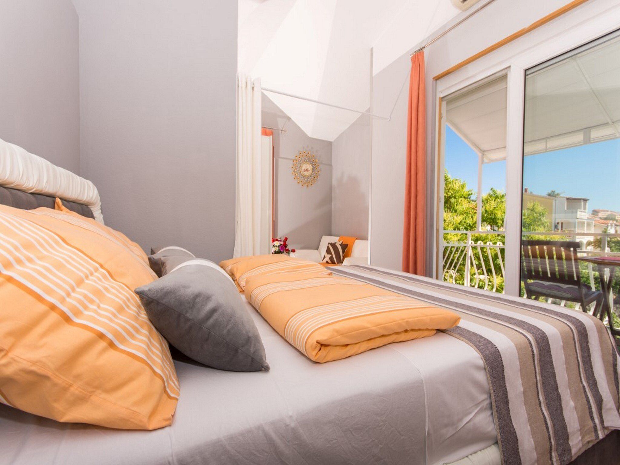A bedroom with a bed, pillows, a window, and a balcony.