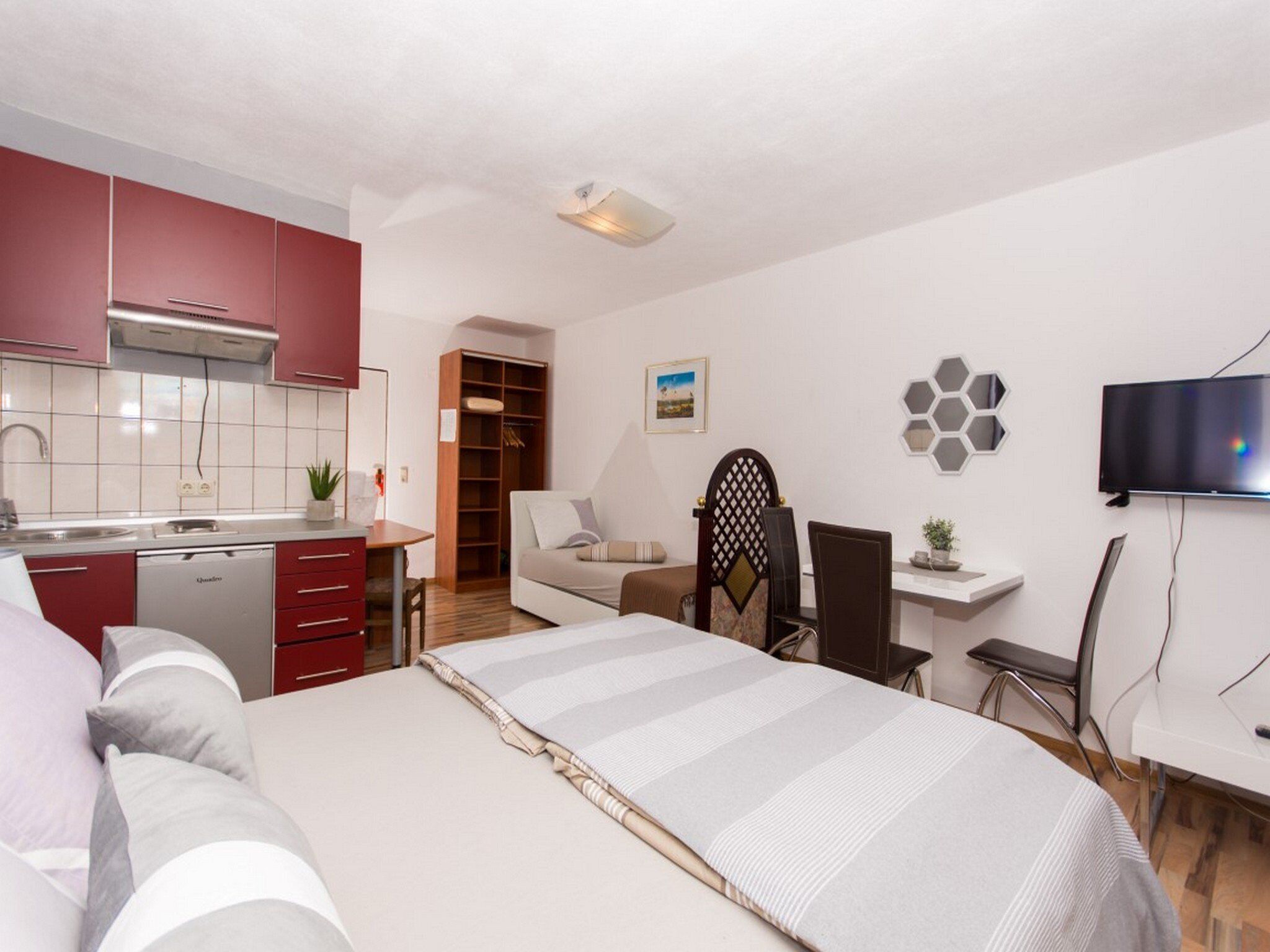 Un estudio compacto con kitchenette, una cama, un escritorio pequeño, un televisor y una zona de estar.