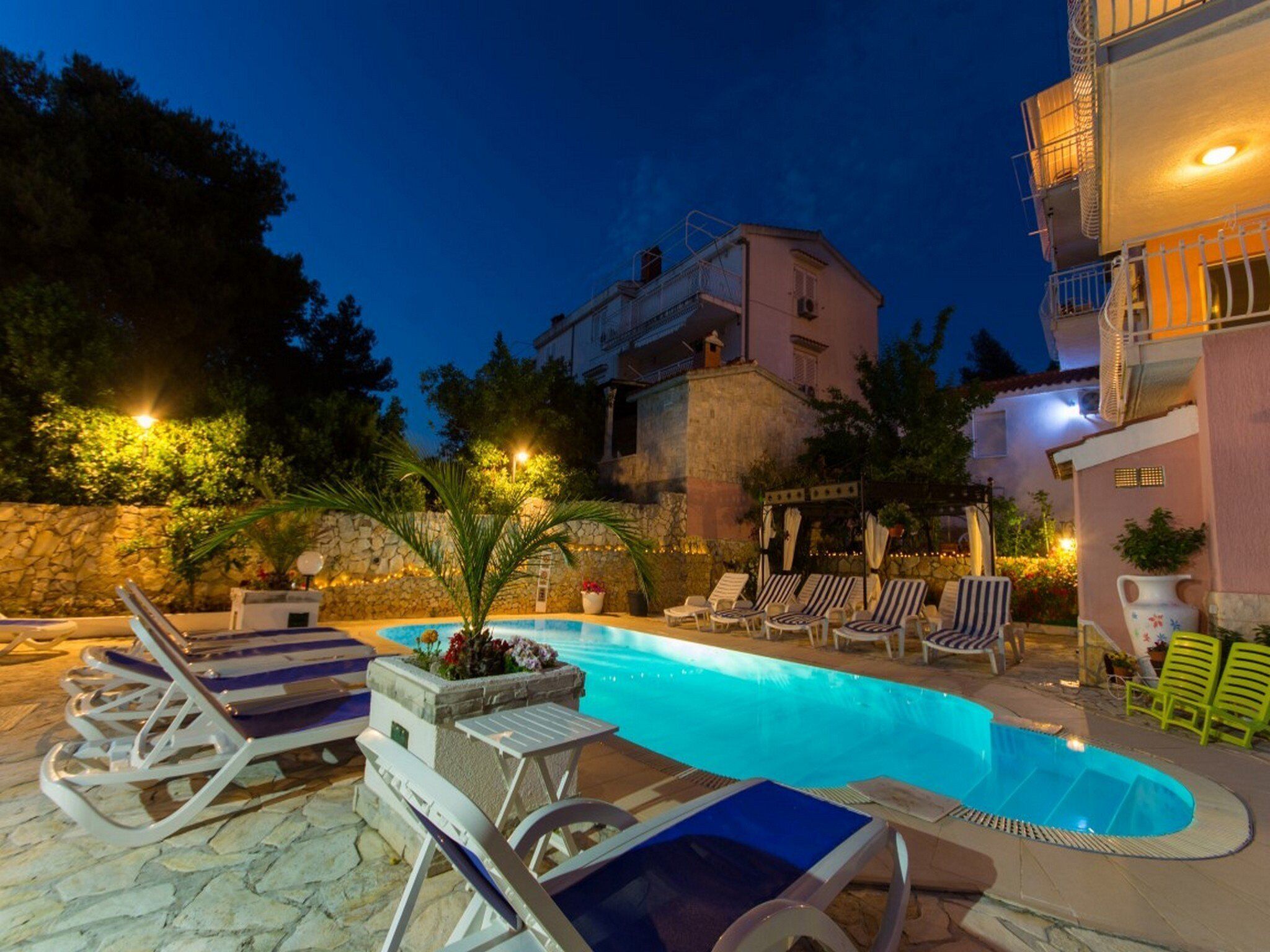 An outdoor swimming pool with lounge chairs and a stone wall.