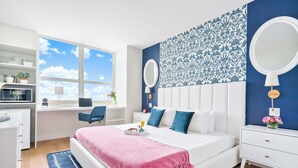 A modern bedroom with a large bed, a desk, and a window with a view of the sky. - Peacock Park Steps Away | Modern Residence (Miami)