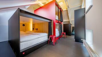 Una habitación de hotel moderna con una cama litera, un escritorio y una pared de acento roja.