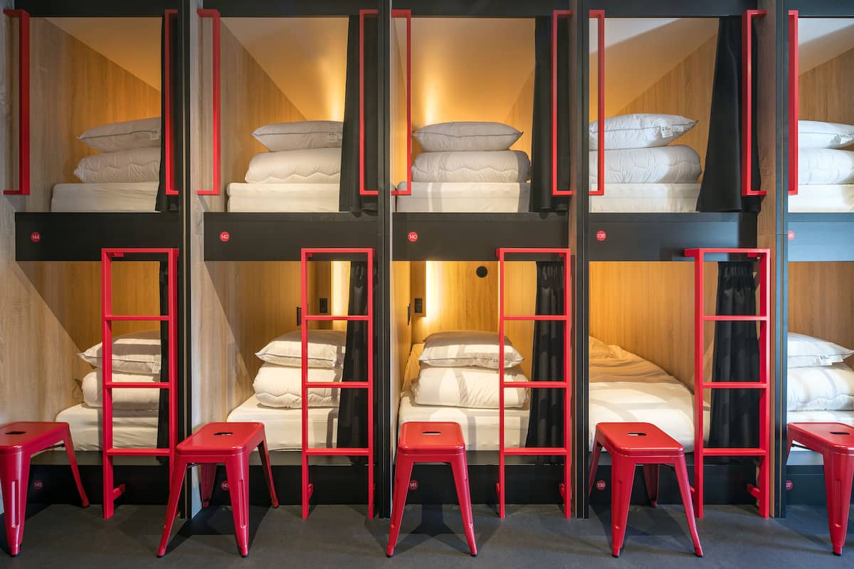 A multi-level bunk bed room with red frames and a central staircase.