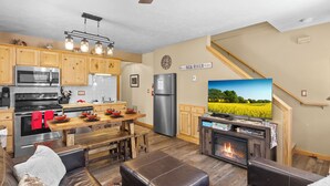 Une cuisine moderne avec des meubles en bois, un réfrigérateur en acier inoxydable et un coin repas comprenant une table et des bancs en bois.