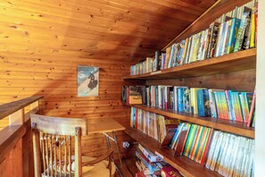 A wooden interior with a bookshelf filled with books, a wooden chair, and a small table.