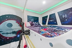 A bedroom with a bed, Star Wars-themed wall art, and a ceiling light. - Kids Bunk Themed Bedrooms | Theater Room | Private Pool with Golf Course Views (Kissimmee)