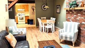 A spacious living area with a wooden loft, a dining set, and a cozy seating arrangement.