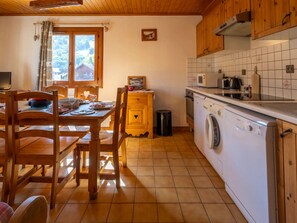 Una cocina con armarios de madera, lavadora y comedor con mesa y sillas.
