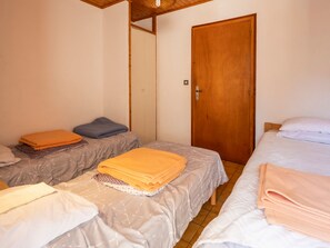 Een kamer met twee bedden, een houten deur en een betegelde vloer.