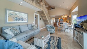 A spacious living room with a grey sofa, patterned cushions, a coffee table, and a staircase leading to an upper level. - 3 Bedroom villa with panoramic Gulf view and sleeps 8, C1824A* (Englewood)