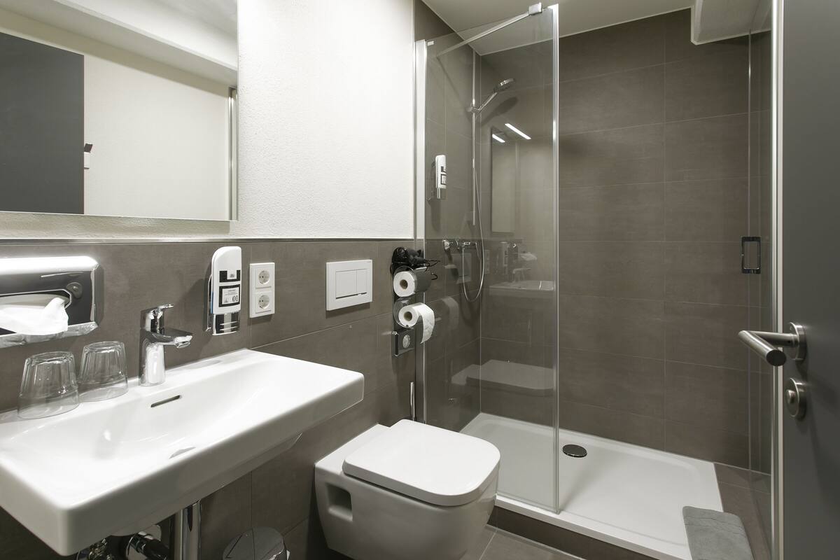 A modern bathroom with a sink, toilet, and glass-enclosed shower.