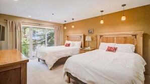 Een slaapkamer met twee bedden, een bureau en een balkon met uitzicht.