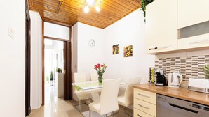A modern kitchen with a glass dining table, white chairs, a dishwasher, and a coffee maker.