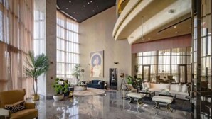 A spacious lobby with a high ceiling, large windows, and a polished marble floor. There are several seating areas with sofas and armchairs, and a few potted plants. - Luxury 2BR Apartment in Paramount Towers Business Bay (Dubai)
