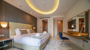 A modern hotel room with a large bed, bedside lamps, a desk, and a mirror. - Luxury 2BR Apartment in Paramount Towers Business Bay (Dubai)