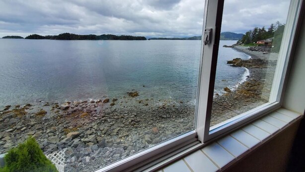 A view of a lake with a rocky shoreline and a distant island. - {Forget-Me-Not Inn} Alaskan Waterfront Vacation Rental (Deer Suite) (Sitka)