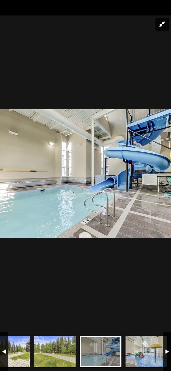 An indoor swimming pool with a blue slide and a staircase.