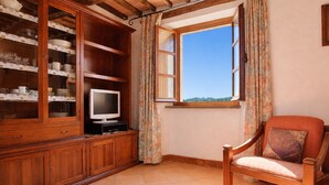 A room with a wooden cabinet, a television, a window with curtains, and a chair. - Nido, in Fetovaia, is a tastefully decorated  two-room apartment , with the terrace overlooking the (Fetovaia)