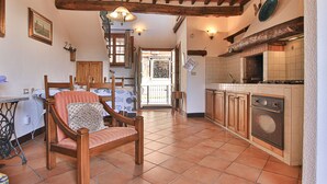 A rustic kitchen with wooden beams, a dining area with a wooden chair and table, and a tiled floor. - Nido, in Fetovaia, is a tastefully decorated  two-room apartment , with the terrace overlooking the (Fetovaia)