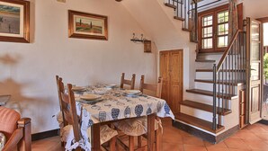 A dining area with a table set for four, a wooden staircase, and a door leading to another room. - Nido, in Fetovaia, is a tastefully decorated  two-room apartment , with the terrace overlooking the (Fetovaia)