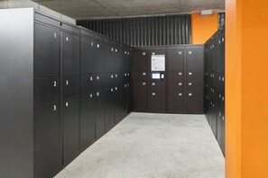 A modern elevator lobby with black lockers numbered 1-38, a concrete floor, and a wall with a vent. - Four Points Flex by Sheraton Madrid Atocha (Madrid)