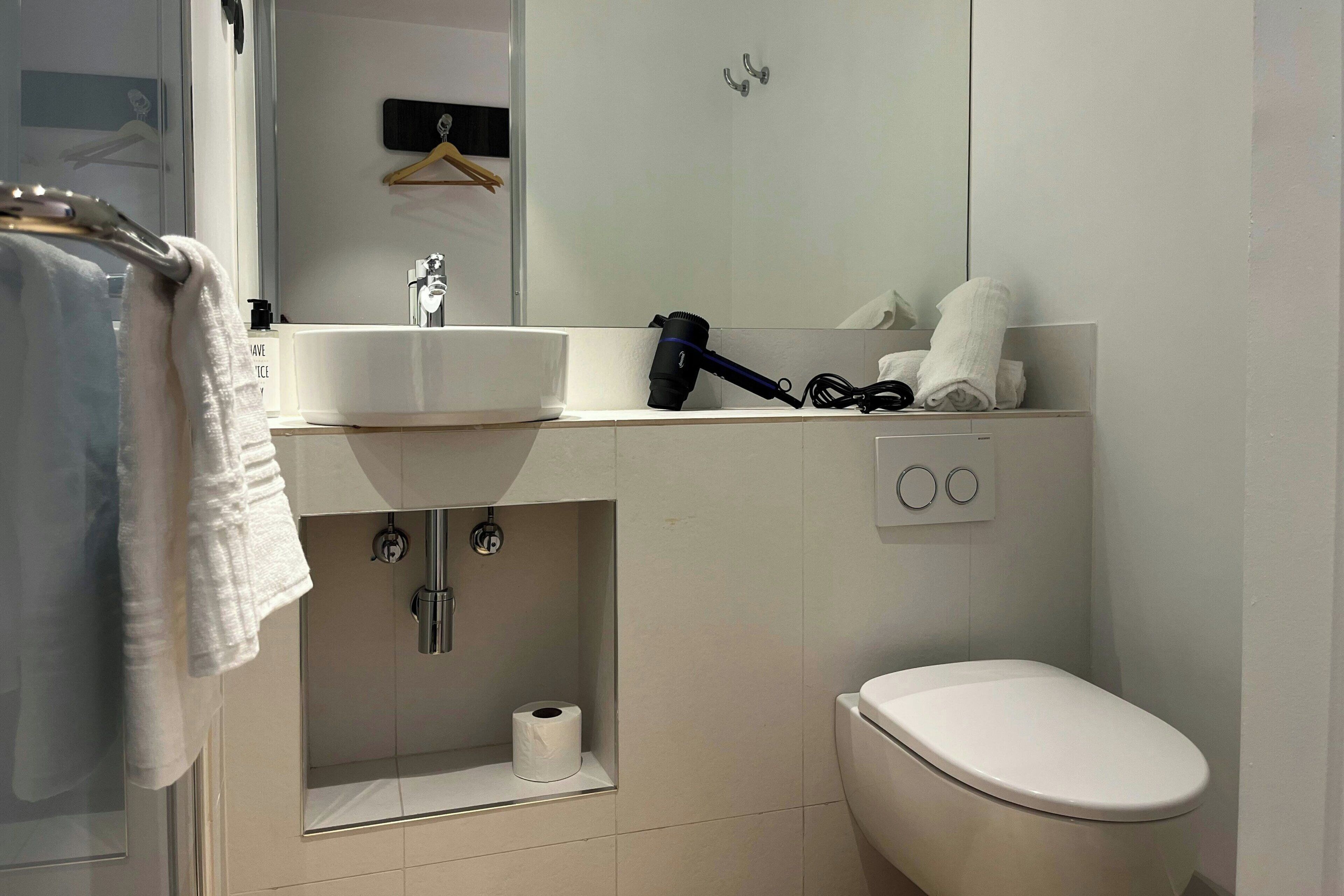 A modern bathroom with a white sink, a toilet, and a towel rack.