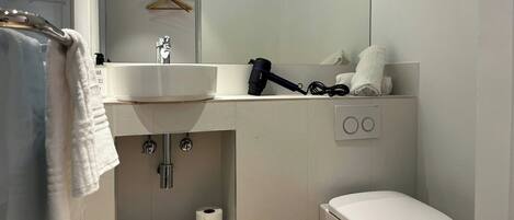 A modern bathroom with a white sink, a toilet, and a towel rack.